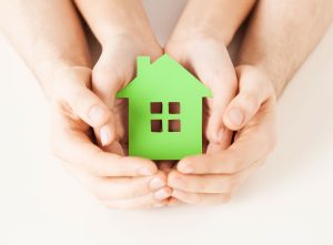 a person holding a green house in their hands.