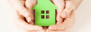 a person holding a green house in their hands.