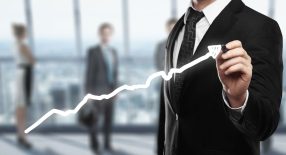 a man in a suit is drawing a line graph.