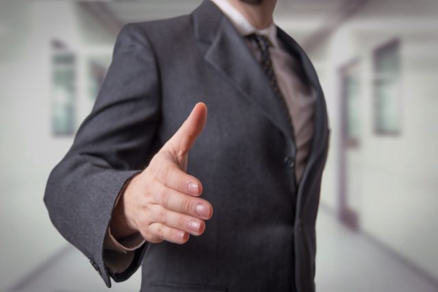 a man in a suit giving a thumbs up.