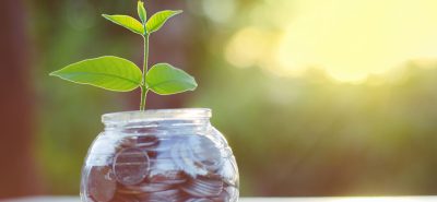 a glass jar filled with coins and a plant growing out of it.