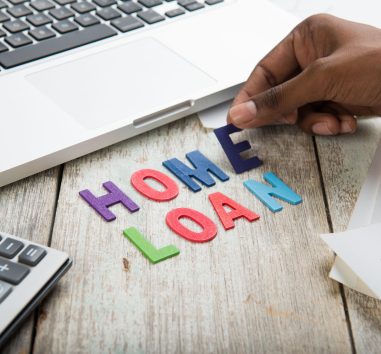 a person is writing the word home loan on a piece of wood.
