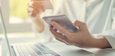 a person holding a credit card while using a laptop.