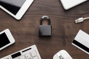 a padlock on a wooden table next to a laptop.