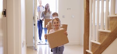 a little girl carrying a cardboard box down a hallway.