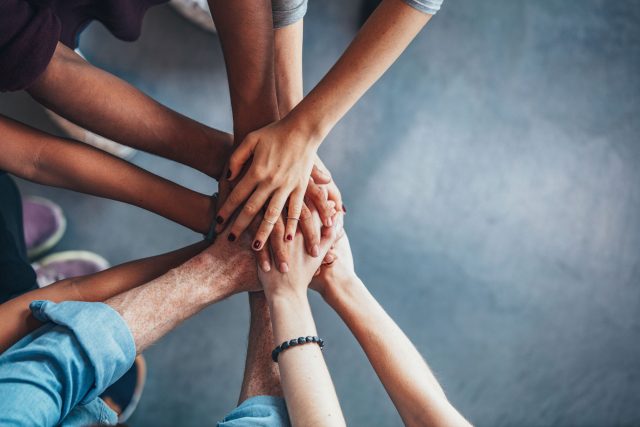 a group of people putting their hands together.