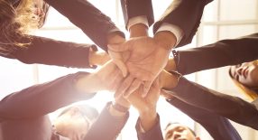 a group of business people stacking their hands together.