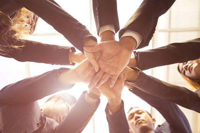 a group of business people stacking their hands together.
