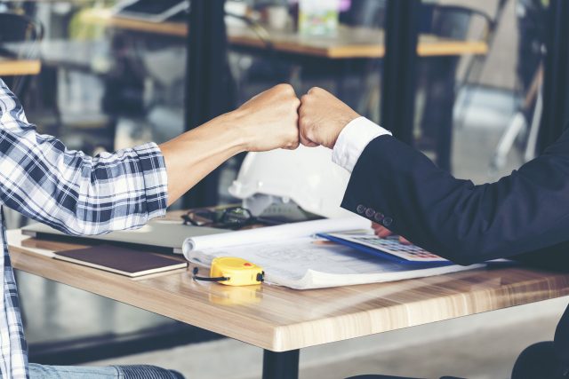 a man and a woman fist bumping hands at a table.