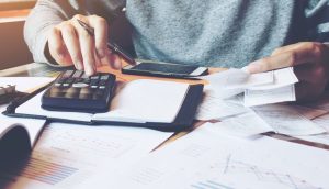 a person sitting at a desk with a calculator.