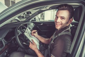 a man sitting in a car holding a clipboard.