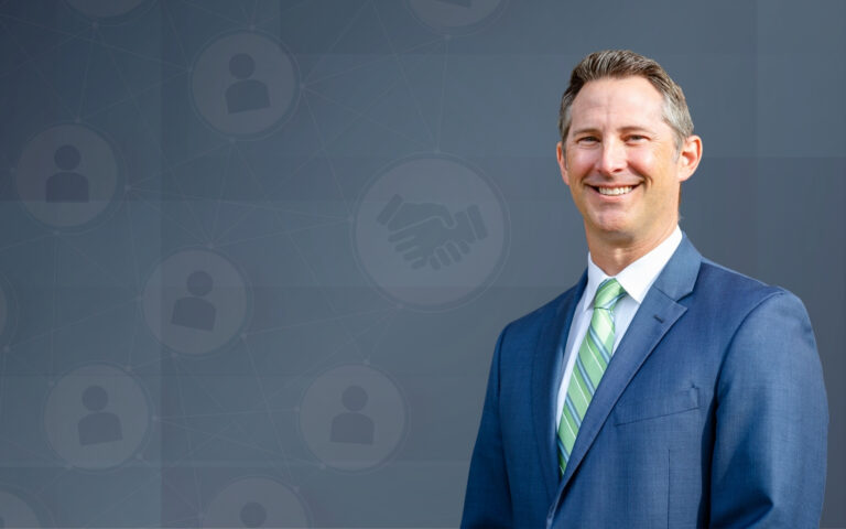 Smiling businessman in a blue suit and green tie against a network-themed blue backdrop, suggesting corporate leadership and networking.